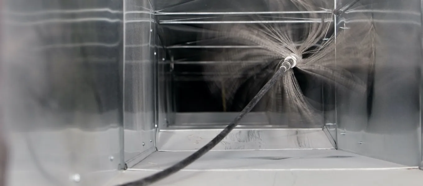 Inside of a duct being cleaned with a rotating brush.
